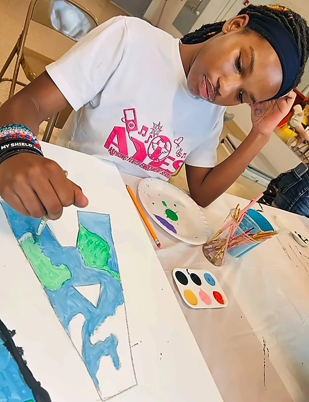 A student in an AYES shirt painting a world map