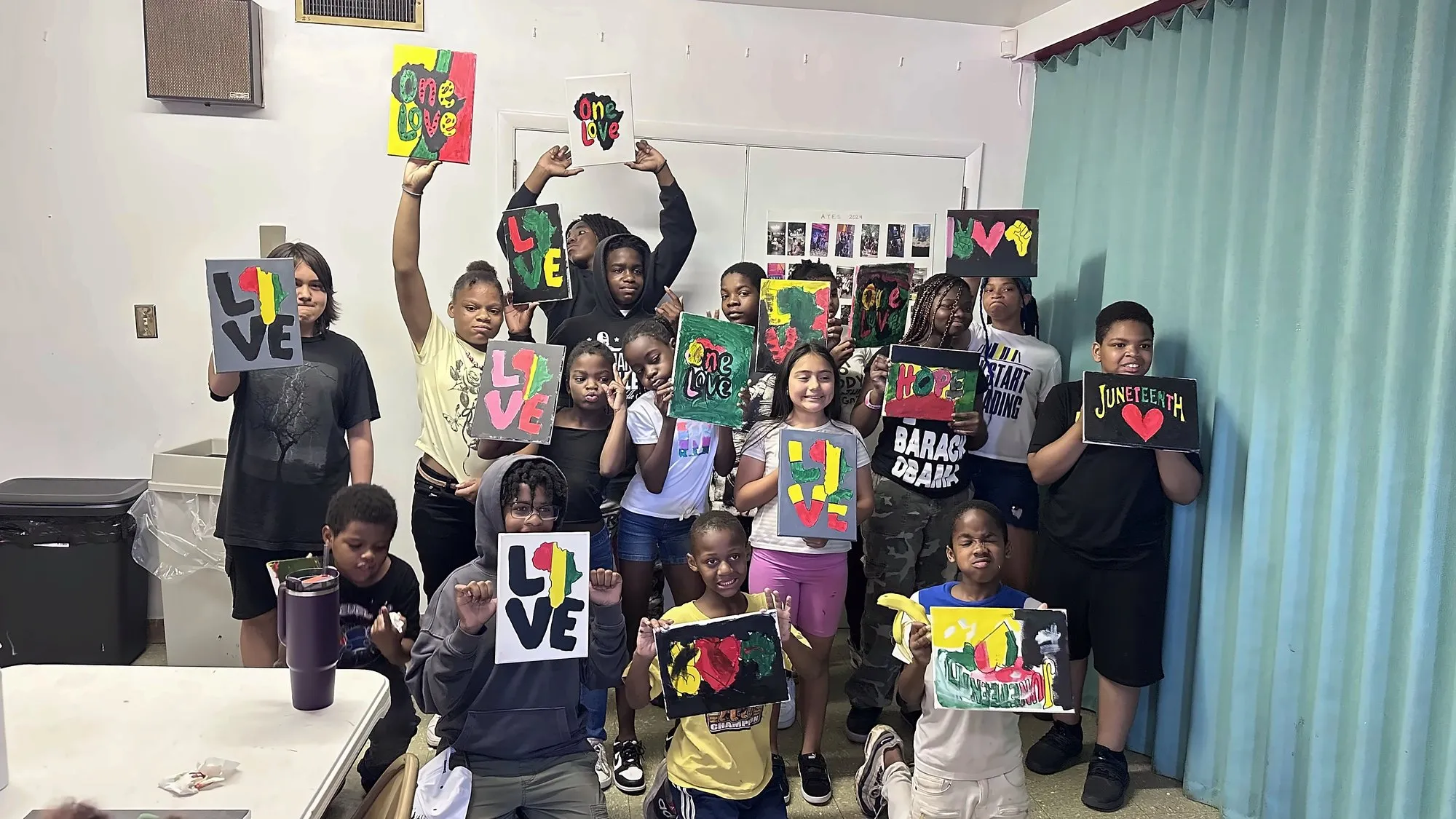 Students holding up the LOVE and One Love paintings they made